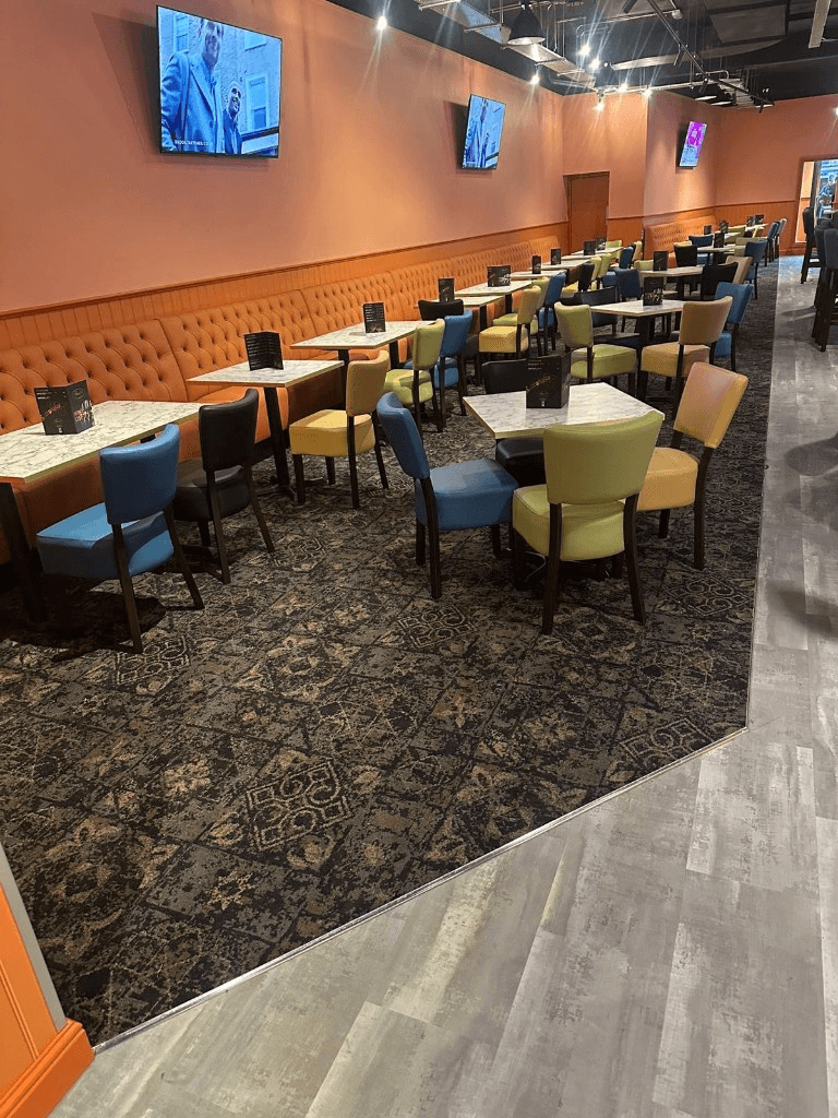 Patterned carpet tiles in a restaurant dining area with LVT walkway — Parfait Flooring, Glasgow